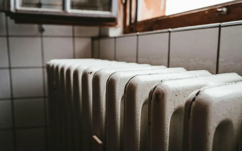 Radiateur blanc sous une fenêtre en bois dans une pièce calme et lumineuse